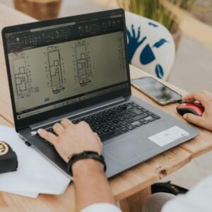 An architect working on building designs using a laptop outdoors, highlighting modern architecture.
